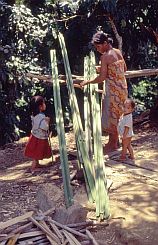 Frau mit zwei Kindern bearbeitet Pflanzenfasern