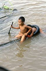 Negara: 2 Jungen schwimmen auf einem Holzbalken im Fluss