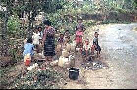 Frauen und Kinder an einer Wasserstelle fllen Kanister mit Trinkwasser