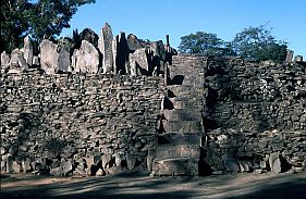 Mauer mit Treppe und Steinstelen in Bena