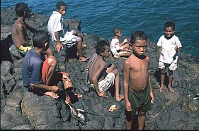 Kinder auf den Felsen am Strand von Lamalera ben sich im Fischen