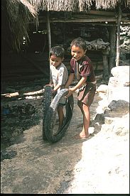Mit einem Reifen spielende Jungen in Tarung