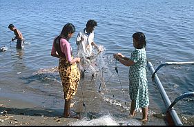 Ein Mann und zwei Frauen sortieren Fischernetze