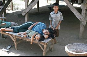 Sarai Bura: Mutter und Kind schlafen auf einer Bank vor ihrem haus