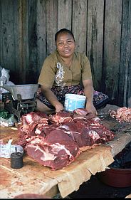 Marktfrau mit Fleisch an ihrem Stand