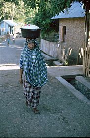 Frau transportiert eine hoch gefllte Schssel mit Reis auf dem Kopf