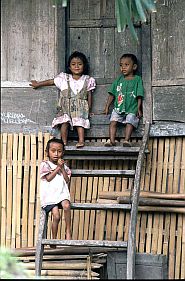 Drei kleine Kinder auf der Leiter vor ihrem Haus