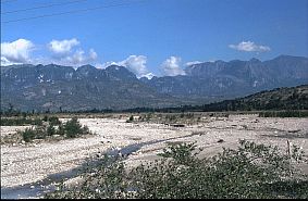 Trockenes Flussbett mit Bergmassiv im Hintergrund